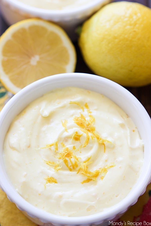 Lemon Mousse in a white bowl with fresh lemons.