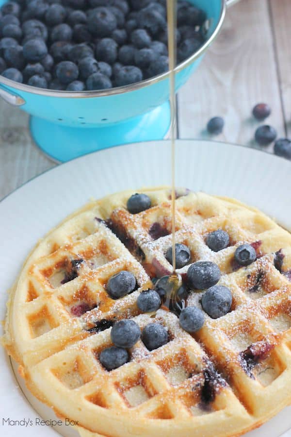 Overnight Blueberry Waffles on a plate with a bowl of blueberries.