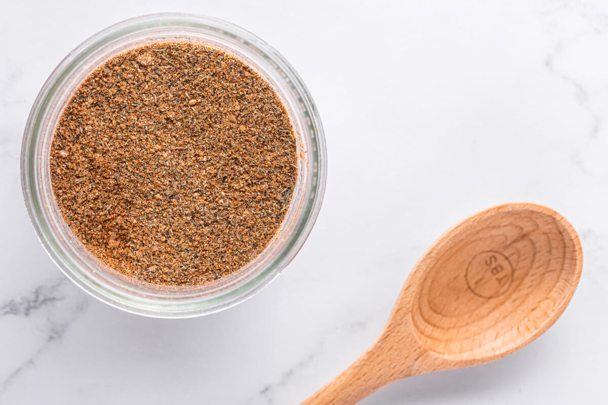 Close up of the dry rub ingredients - kosher salt, brown sugar, paprika, garlic powder, cumin, and black peppercorns.