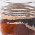 Close up of the dry rub ingredients - kosher salt, brown sugar, paprika, garlic powder, cumin, and black peppercorns.
