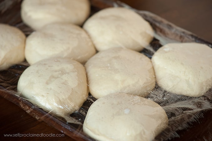 hamburger bun dough with a piece of plastic wrap on top