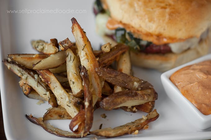 rosemary garlic baked fries next to a burger on plate