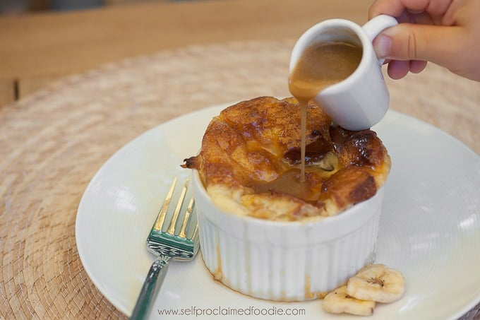 serving of bread pudding with rum sauce getting poured on top 