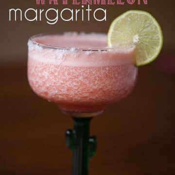 a glass of blended watermelon margarita with lime garnish