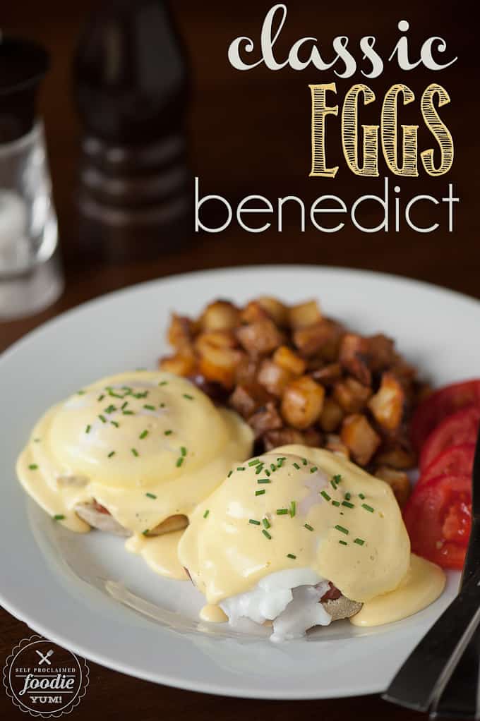 A plate of classic eggs Benedict with potatoes and tomatoes on the side