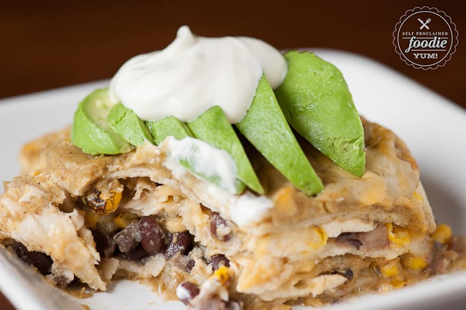 a close up of black bean and corn green chile enchilada casserole with bite taken out