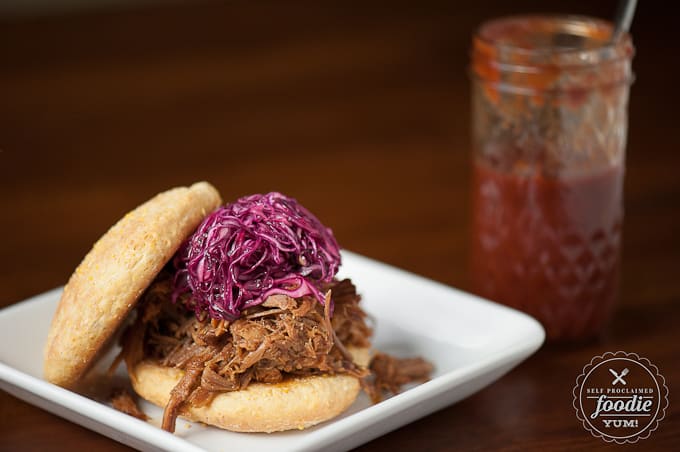 pulled pork sandwich topped with purple cabbage slaw and bbq sauce