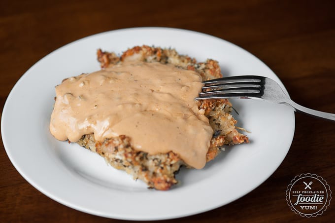 breaded chicken breast covered in cheese sauce on plate