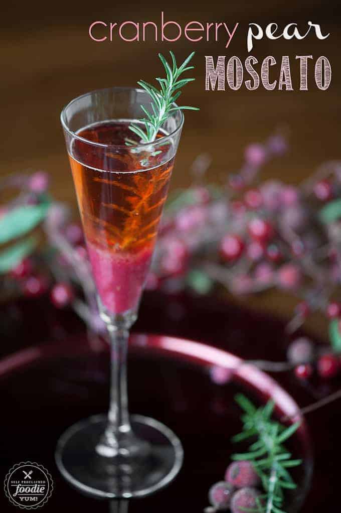 champagne flute with a cranberry pear moscato cocktail with rosemary garnish