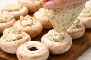 piping cheese mixture into boursin stuffed mushrooms.