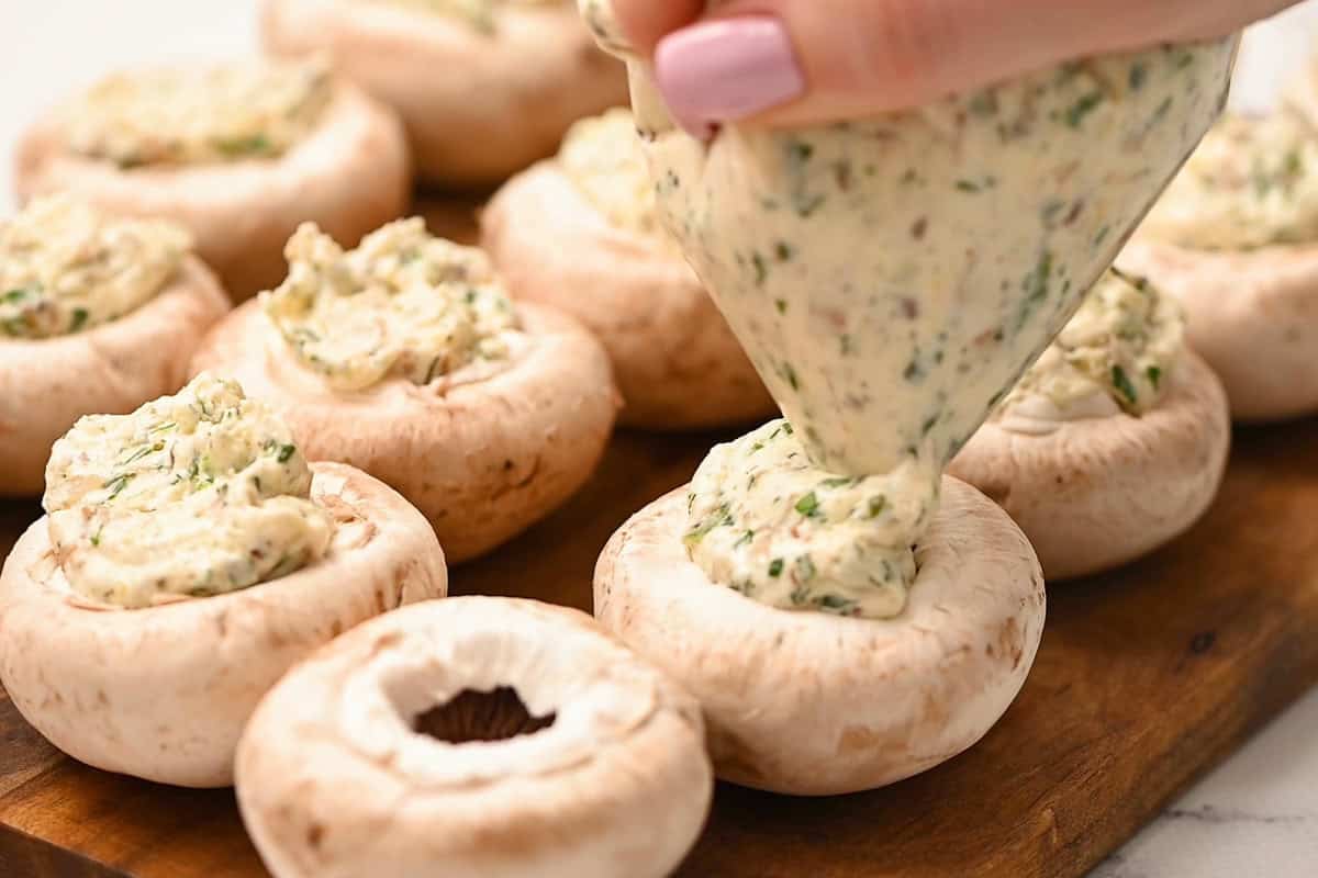 piping cheese mixture into boursin stuffed mushrooms.
