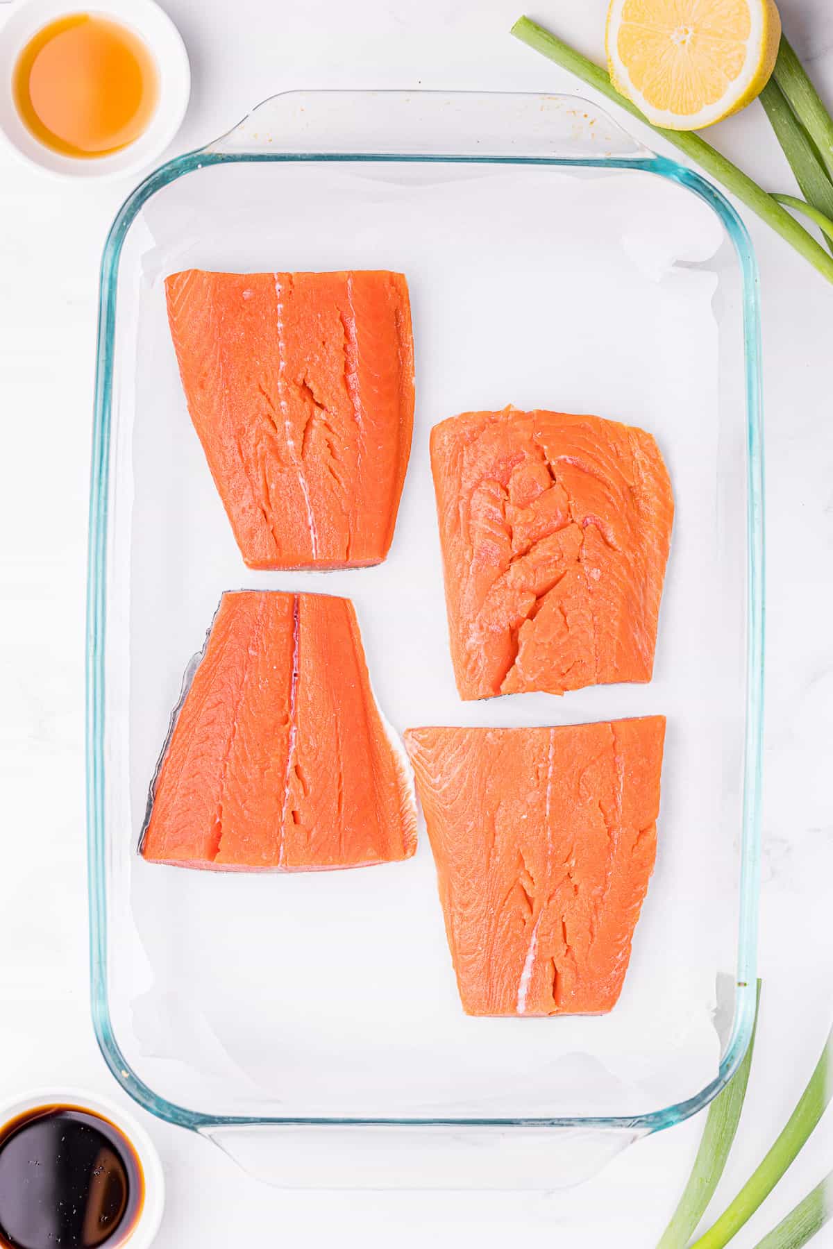 Salmon fillets arranged in a single layer on a parchment lined baking sheet ready for the oven.
