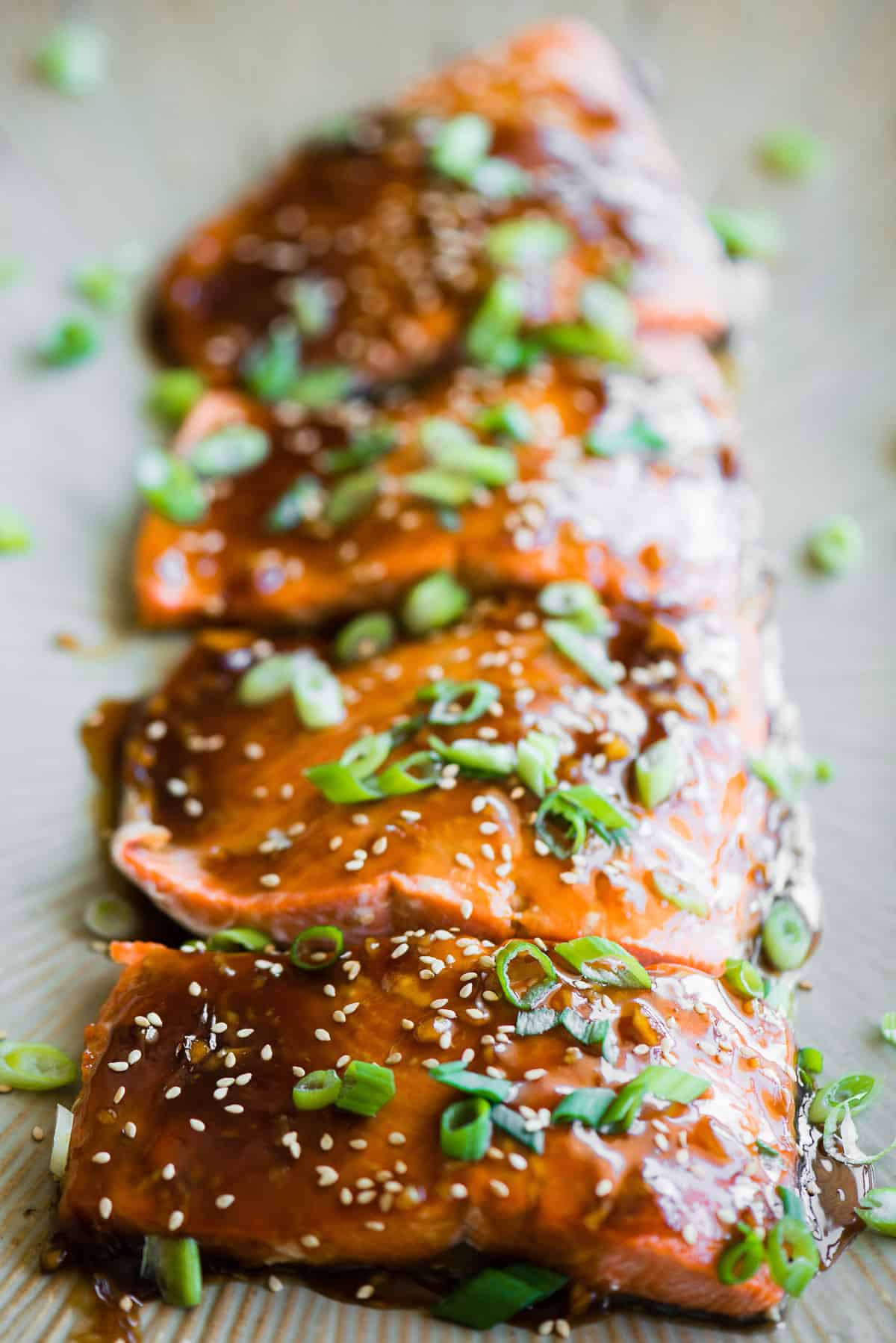 whole fresh salmon filet baked with teriyaki sauce and garnished with green onions and sesame seeds.