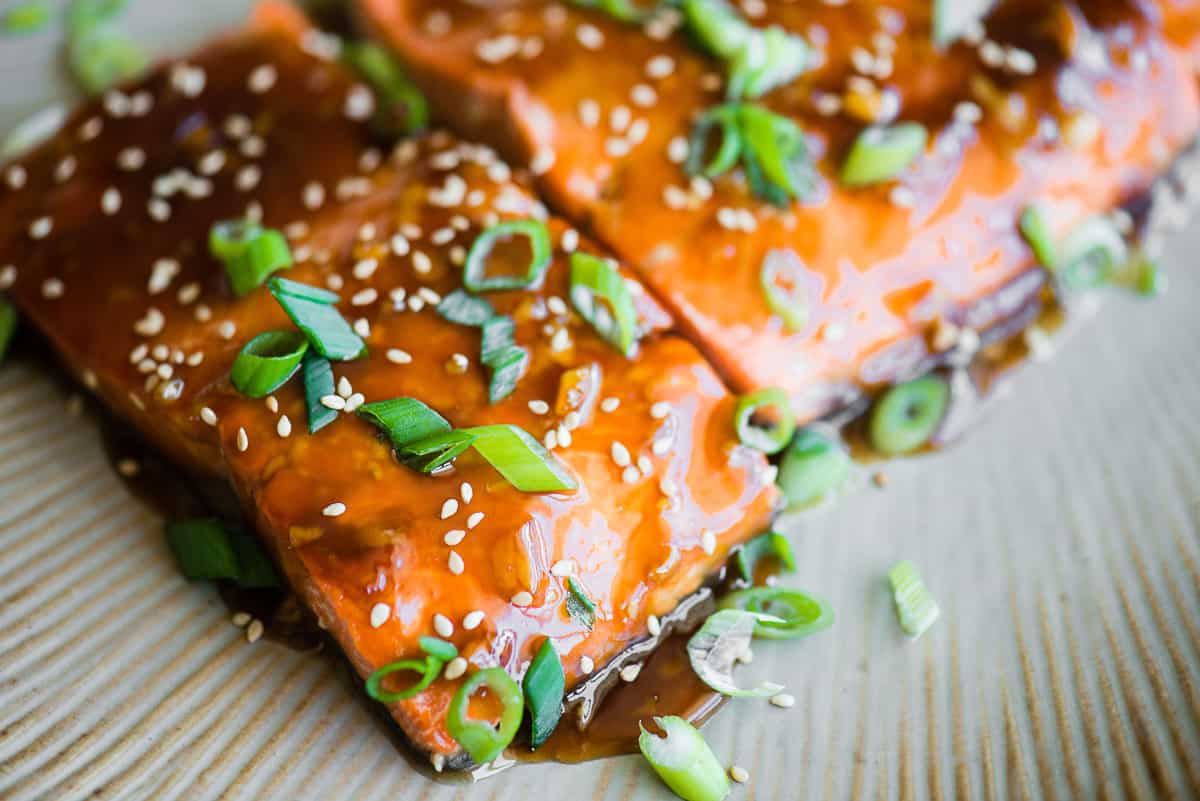 Close up of baked teriyaki salmon garnished with green onion slices.