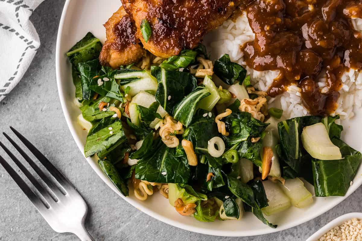 Homemade bok choy salad with a crunchy ramen almond topping on plate next to apricot glazed chicken and rice.