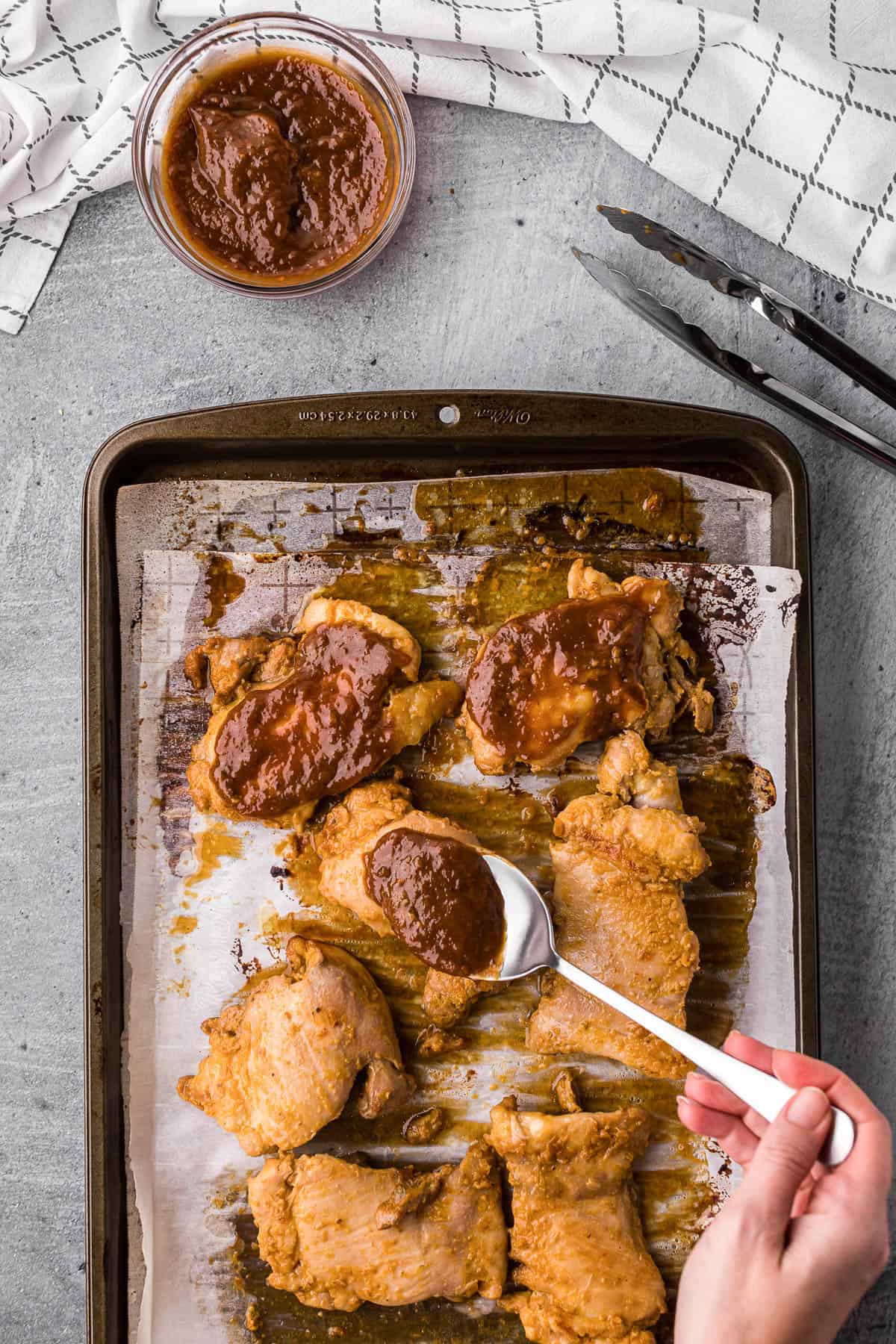 apricot glazed chicken thighs on baking sheet with small bowl of glaze.