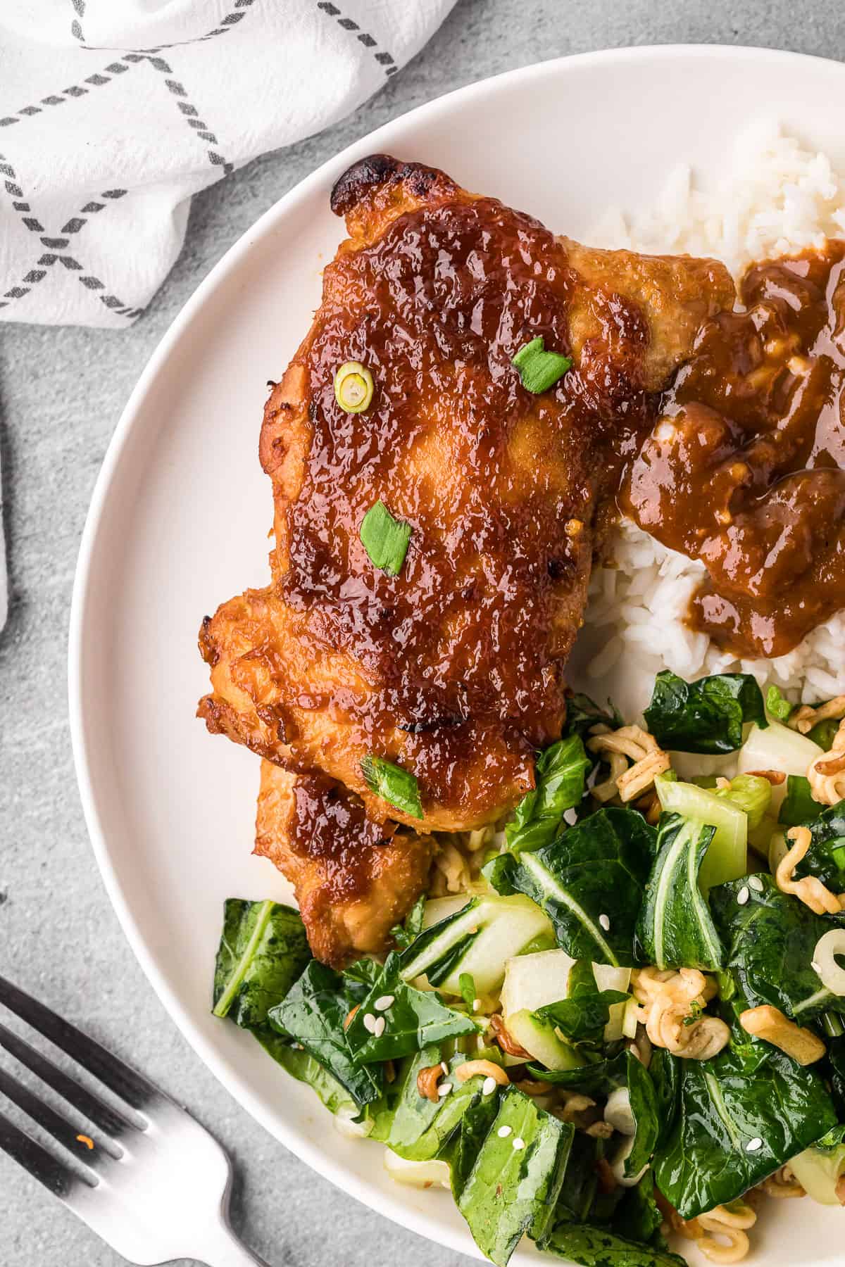 apricot glazed chicken boneless chicken thigh on white plate with bok choy salad and white rice.