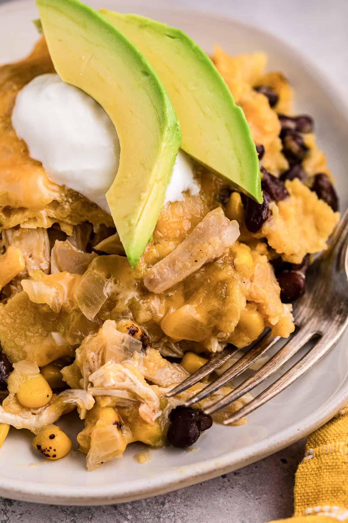 Green Chile chicken enchilada casserole with black beans and corn topped with avocado and sour cream.