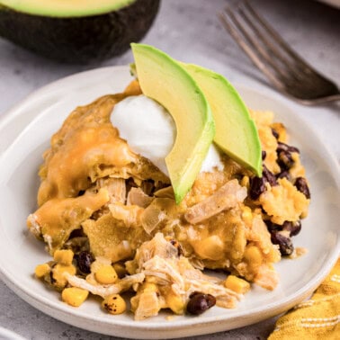 Green Chile chicken enchilada casserole with black beans and corn topped with avocado and sour cream.