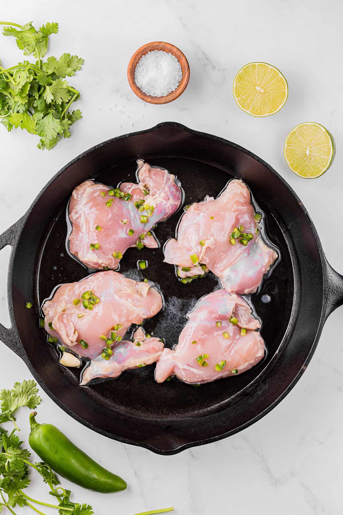 Cooking jalapeno marinated boneless skinless chicken thighs in cast iron pan.