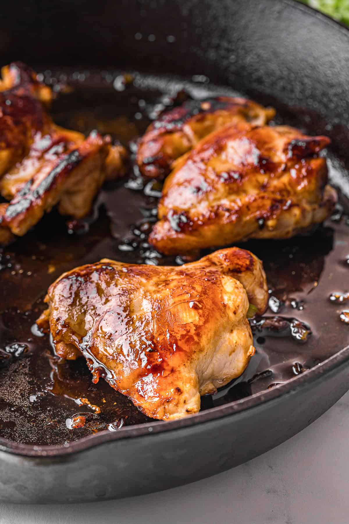 browned marinated chicken thighs cooked in a cast iron pan.