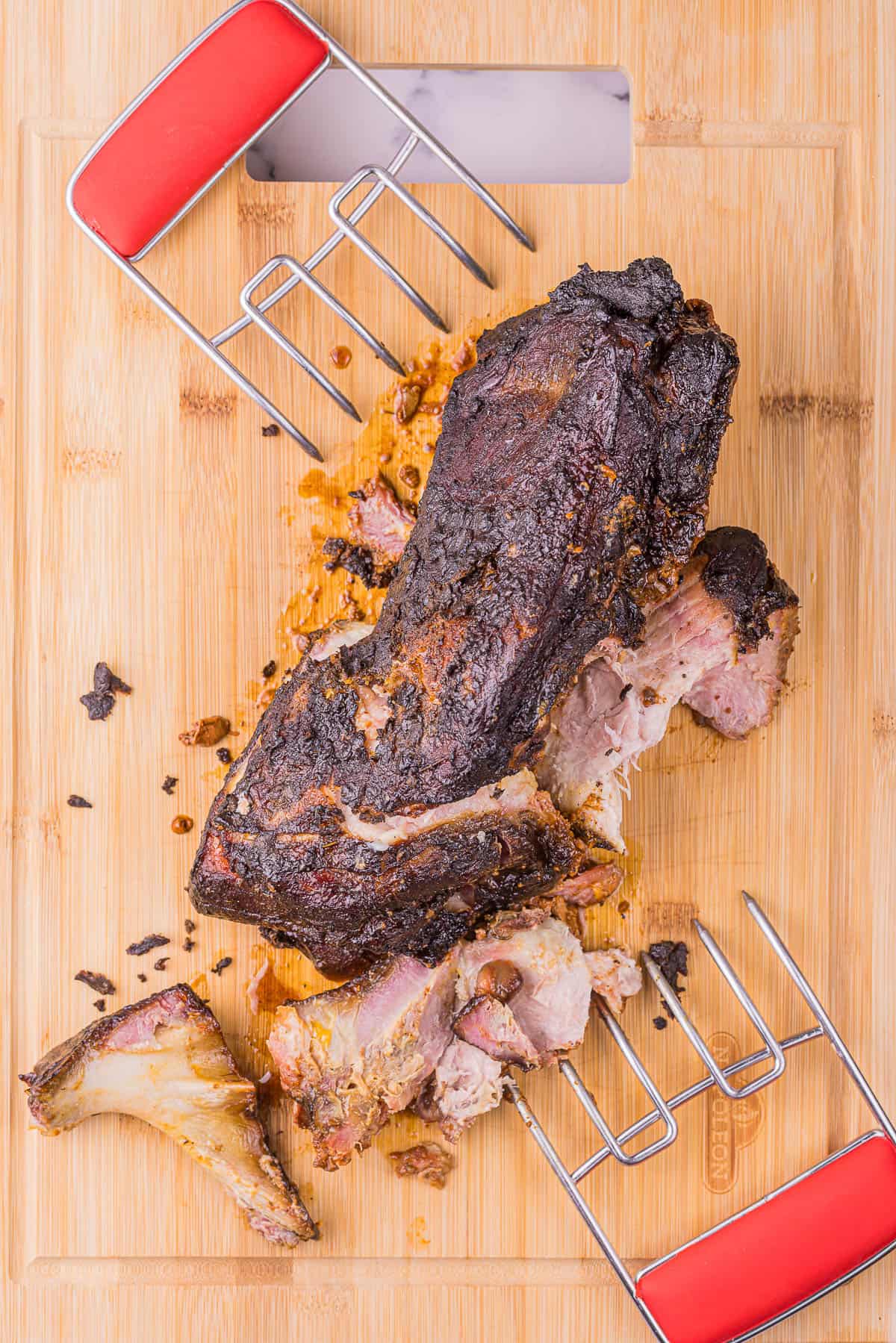 top down view of a smoked pork butt that is being shredded on a cutting board.