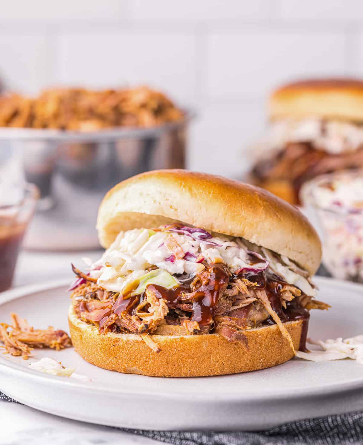 smoked pulled pork sandwich topped with barbecue sauce and coleslaw.