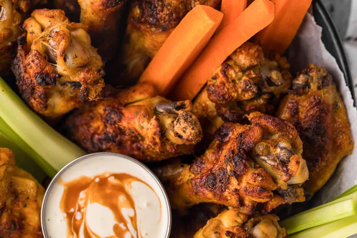 basket of homemade spicy ranch chicken wings with carrot and celery sticks and dipping sauce.