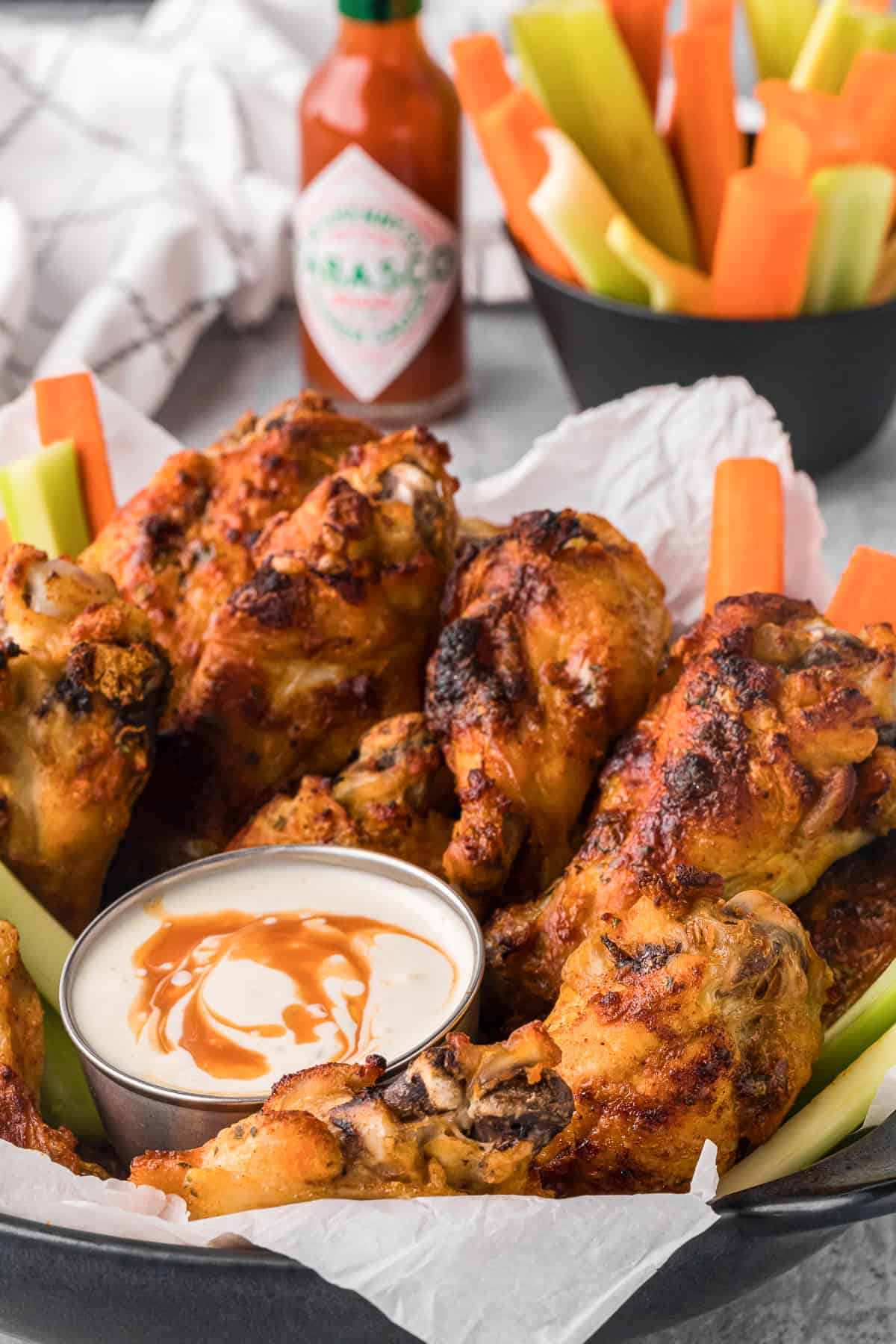 basket of homemade spicy ranch chicken wings with carrot and celery sticks and dipping sauce.