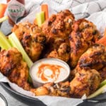 basket of homemade spicy ranch chicken wings with carrot and celery sticks and dipping sauce.