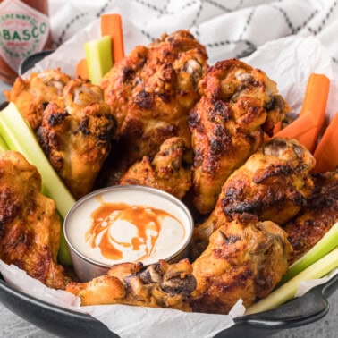 basket of homemade spicy ranch chicken wings with carrot and celery sticks and dipping sauce.