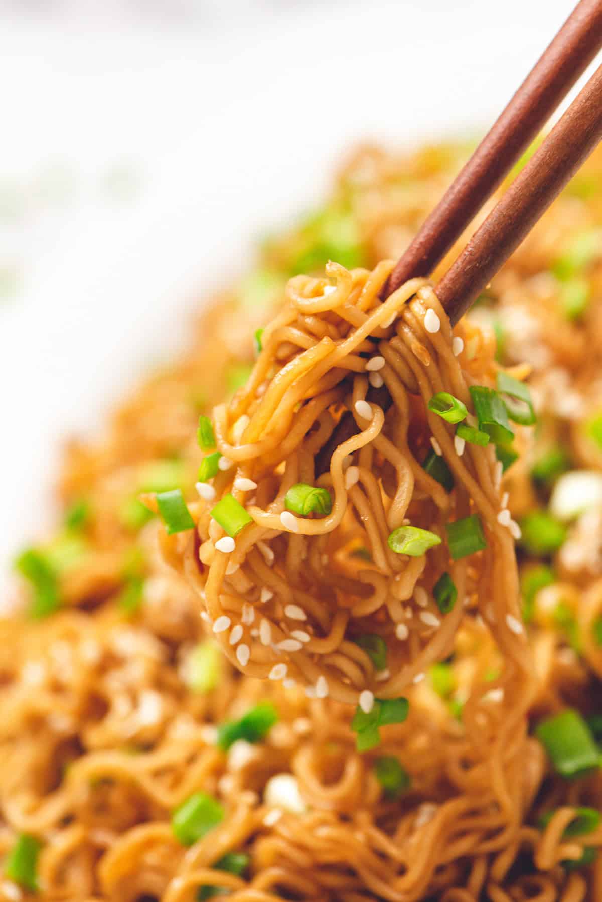 instant ramen noodles with green onions picked up with chop sticks.