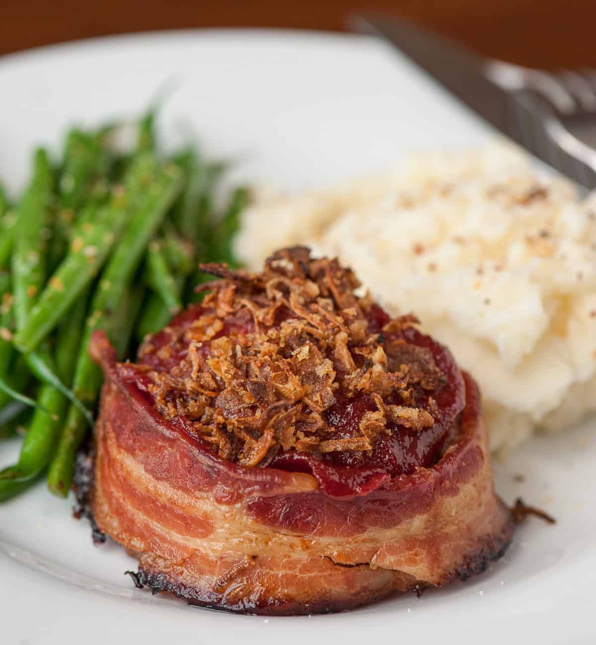 bacon wrapped meatloaf with crispy onions on top.