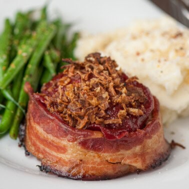 bacon wrapped meatloaf with crispy onions on top.