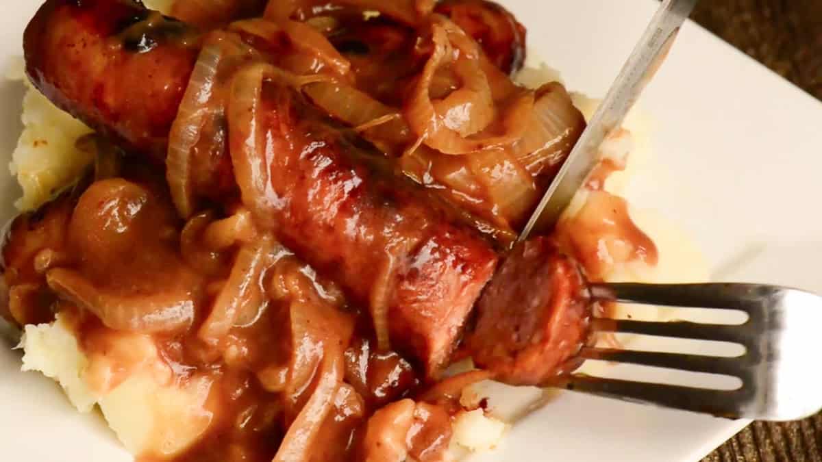 cutting bite of Guinness Bangers and Mash with Onion Gravy.