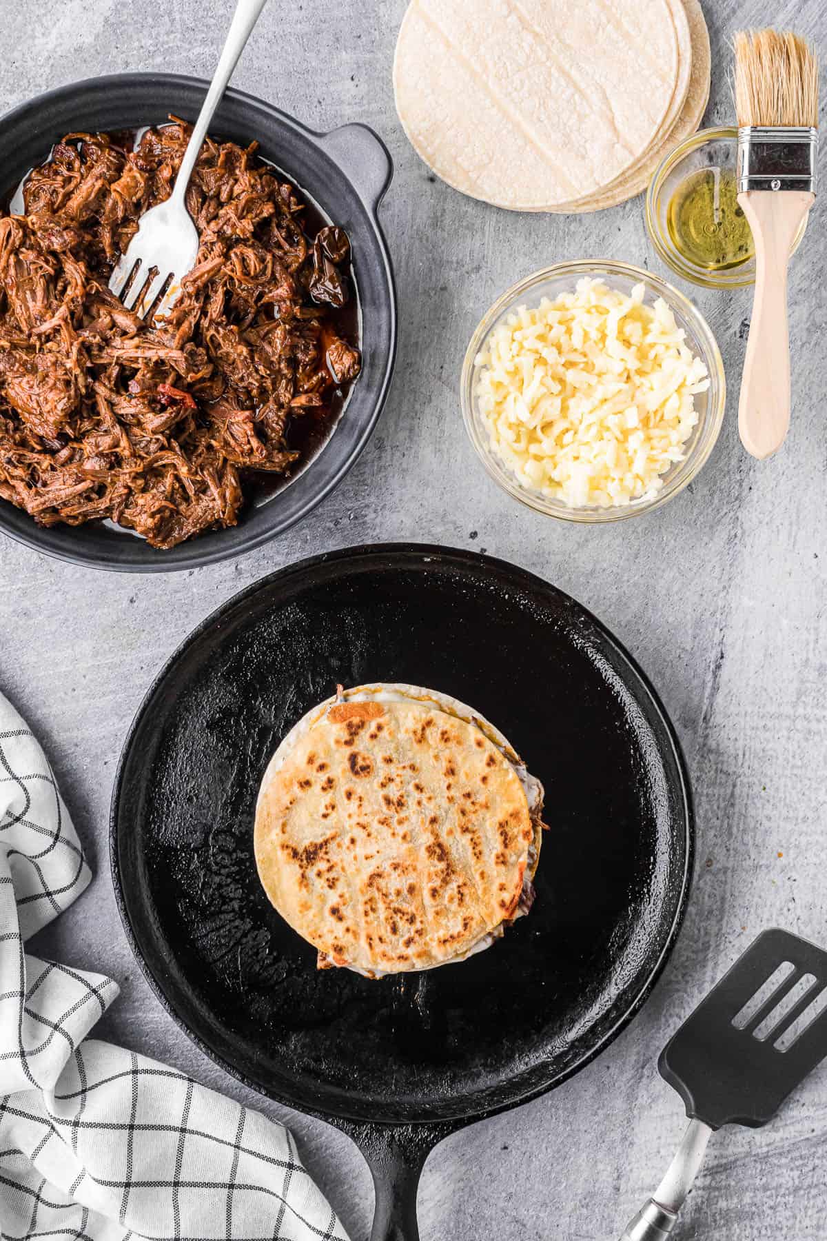 making a quesadilla with cheese and barbacoa beef.