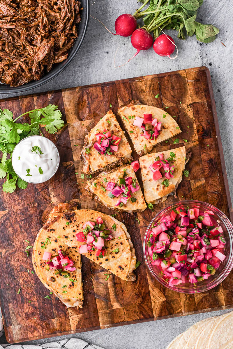 barbacoa quesadillas with quick pickled radishes on wood cutting board.