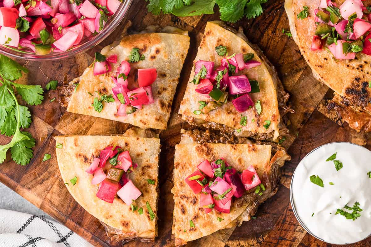 barbacoa quesadillas with quick pickled radishes on wood cutting board.