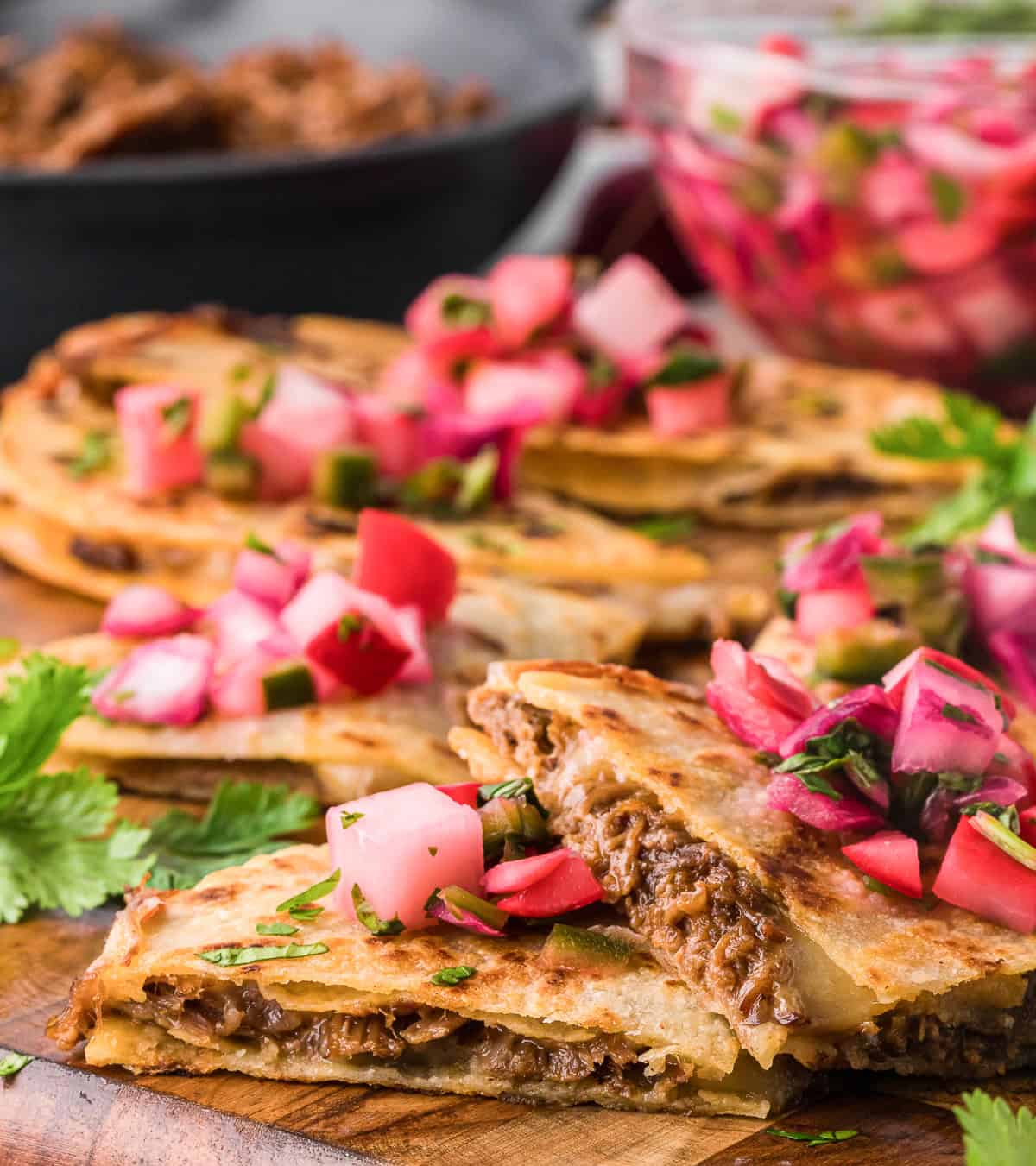 barbacoa quesadillas with quick pickled radishes on wood cutting board.