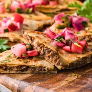 barbacoa quesadillas with quick pickled radishes on wood cutting board.