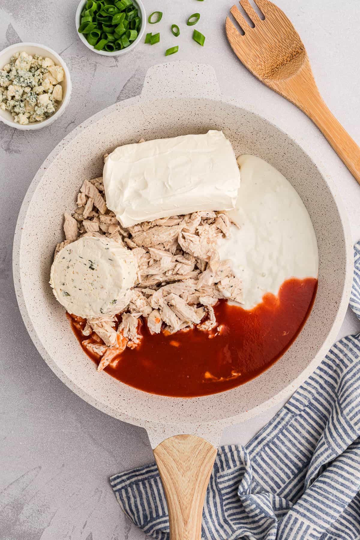 Ingredients needed to make warm buffalo chicken dip in a pan.