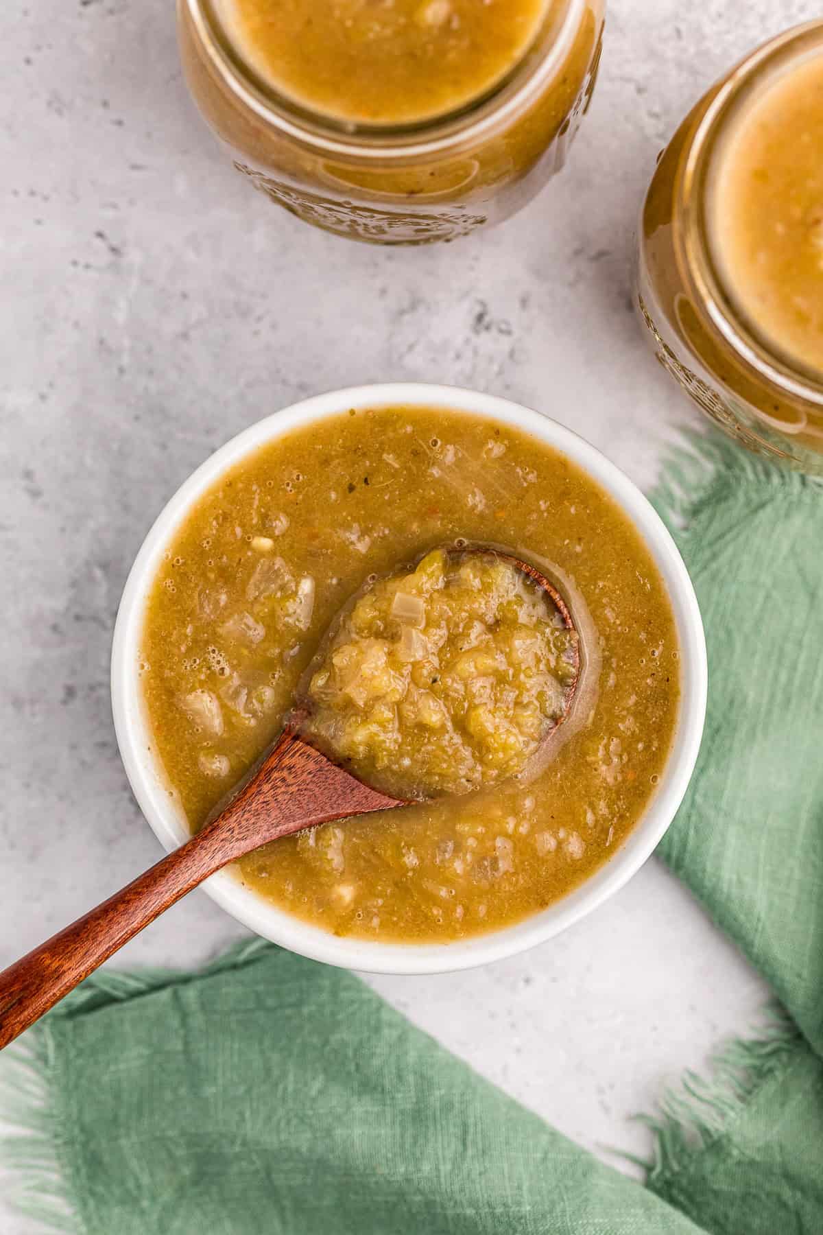 homemade green enchilada sauce in white bowl with spoon.