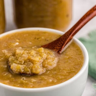 homemade green enchilada sauce made with Hatch green chile in white bowl with wood spoon.