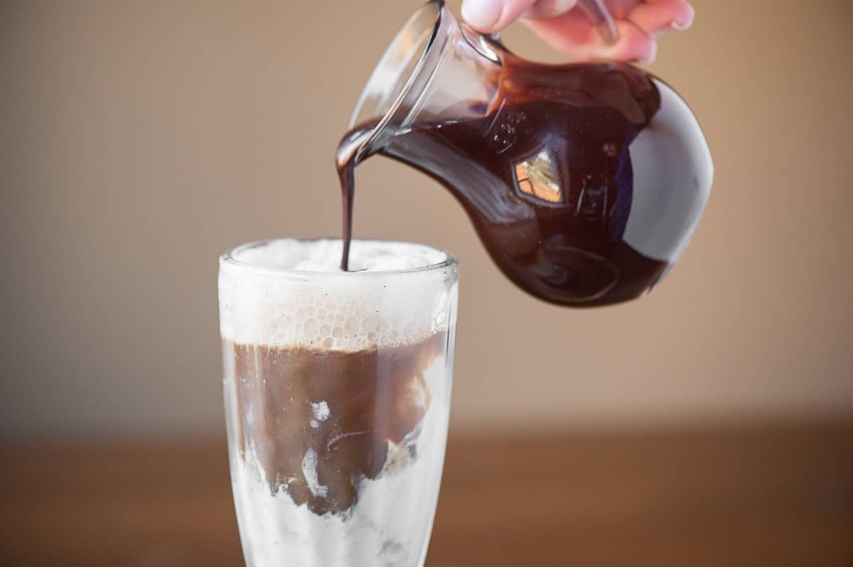 pouring chocolate sauce over guinness float.