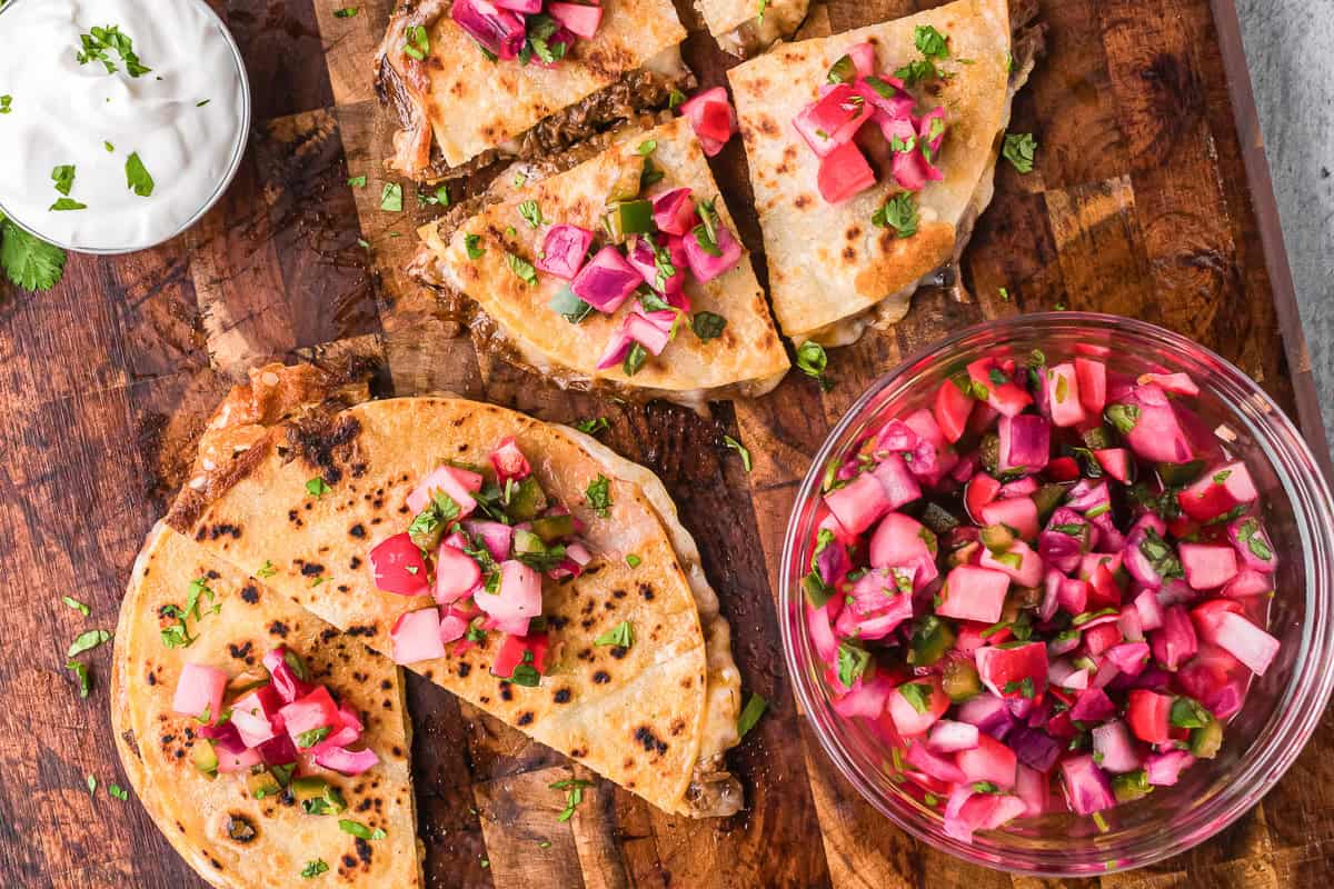 bowl of quick pickled radishes next to crispy quesadillas.