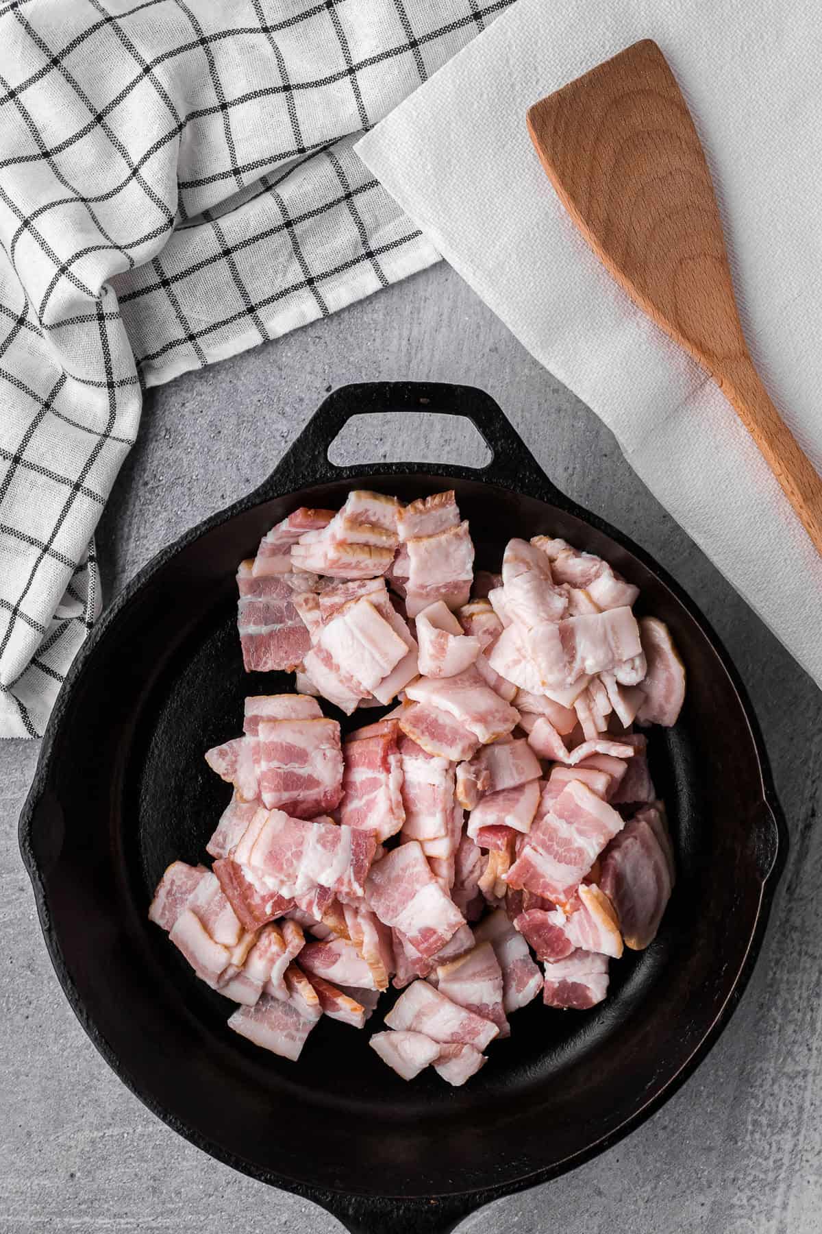 chopped bacon pieces in a cast iron pan.