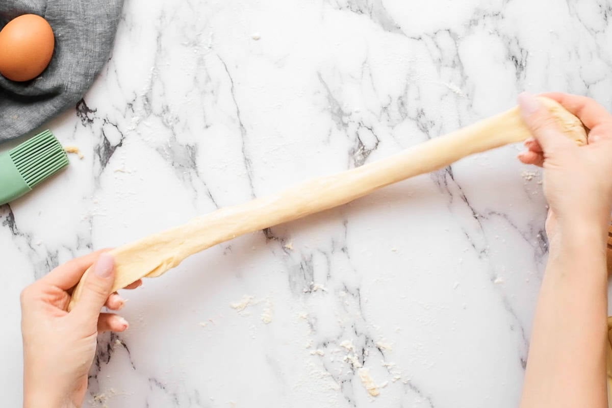 stretching a piece of homemade challah bread dough.