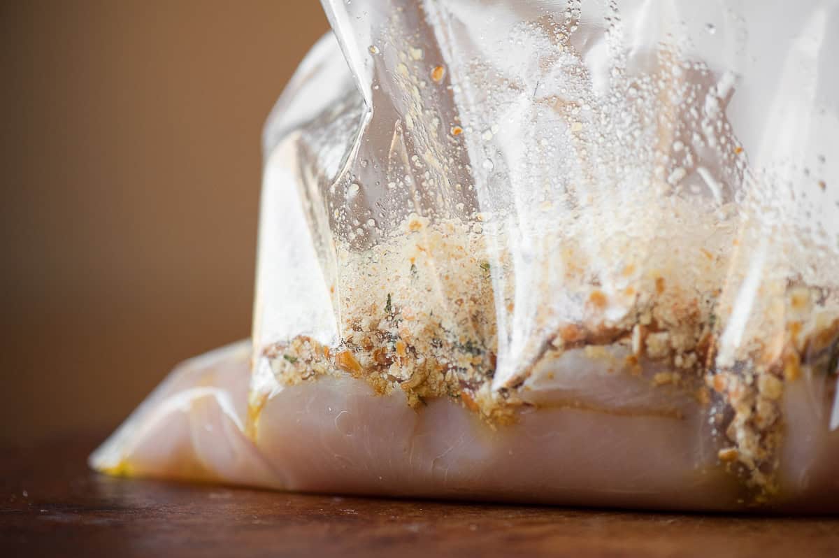 chicken breasts with pretzel crumbs and oil in plastic bag.