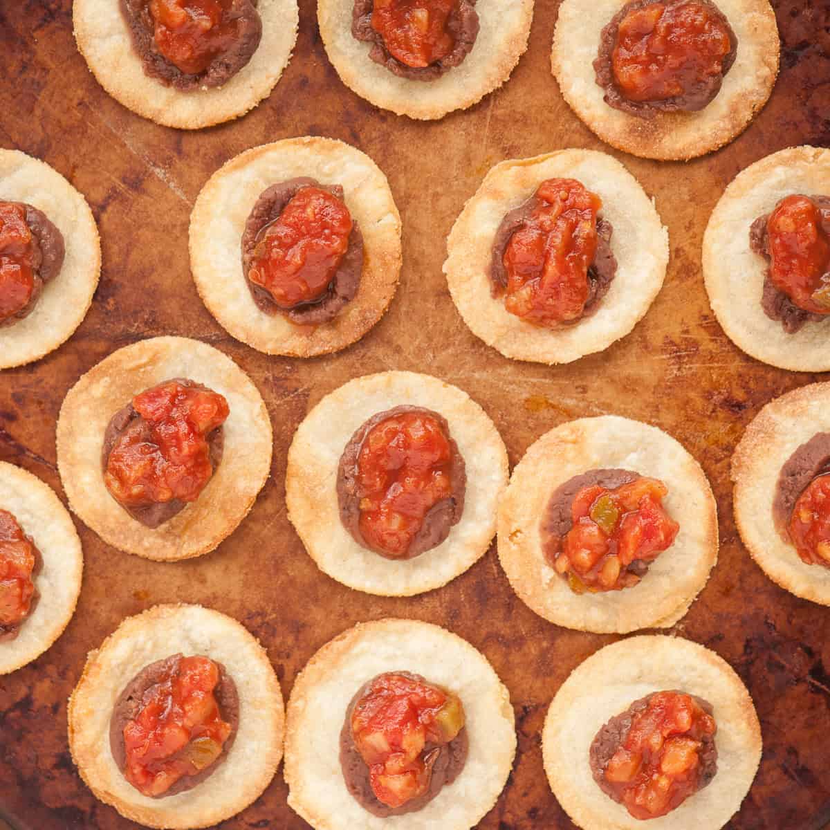 small tortilla rounds with refried beans and salsa.