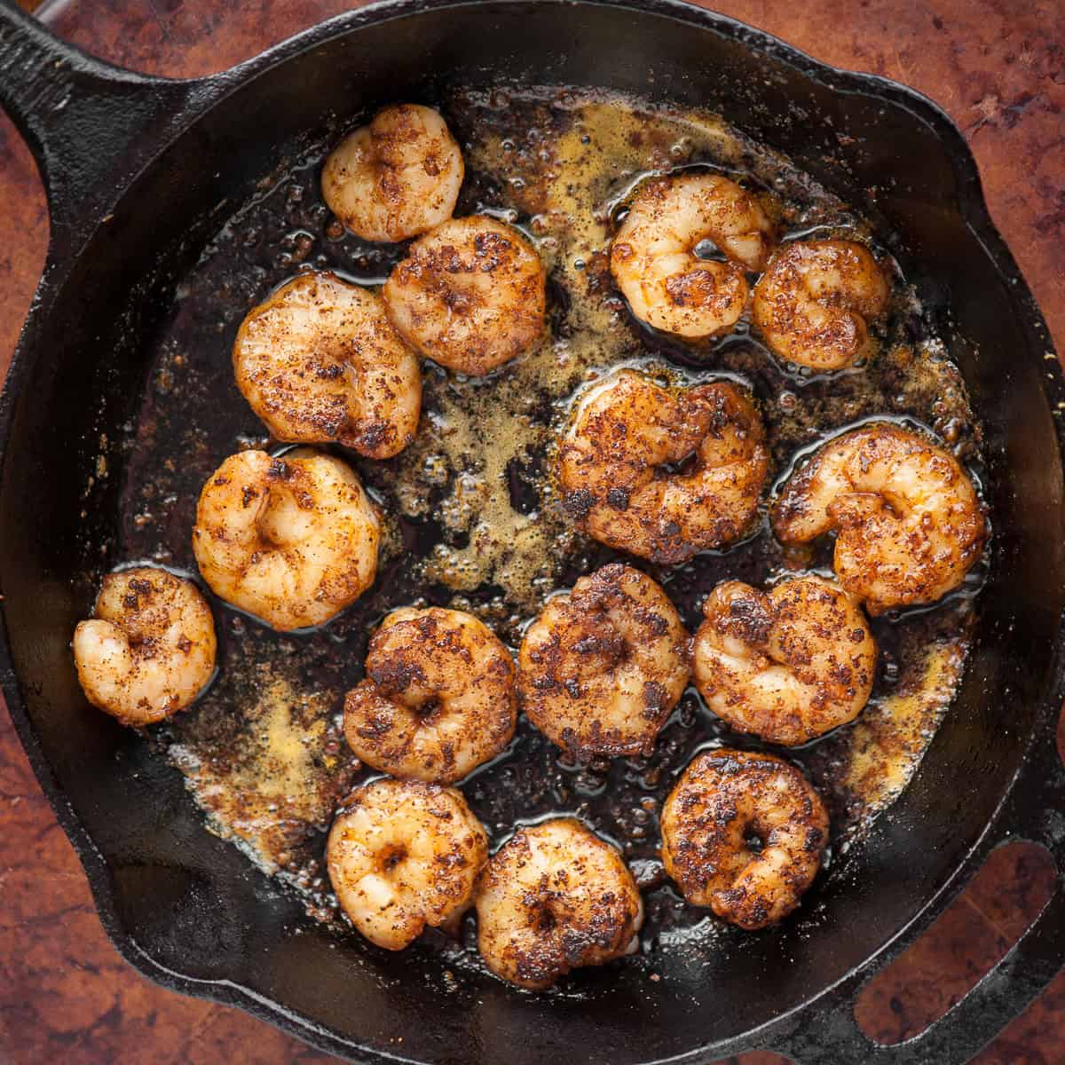 cooking shrimp in cast iron pan with seasonings.